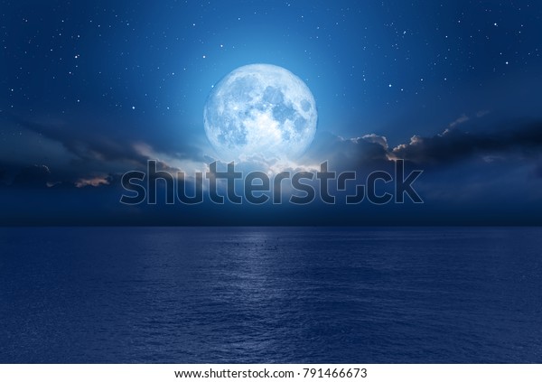 Night sky with blue moon in the clouds over the calm\
blue sea, many sytars in the background  \