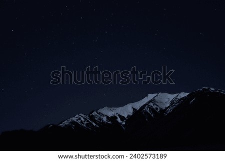 A night sky with countless stars twinkling brightly above snow-capped mountain peaks