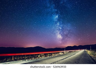 Night Sky With Milky Way And Stars. Night Road Illuminated By Car. Light Trails Colorful Galaxy