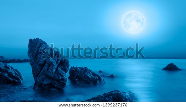 Night sky with moon in the clouds
foreground calm sea