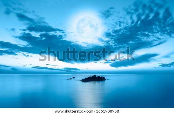 Night sky with moon in the\
clouds on the foreground calm sea\