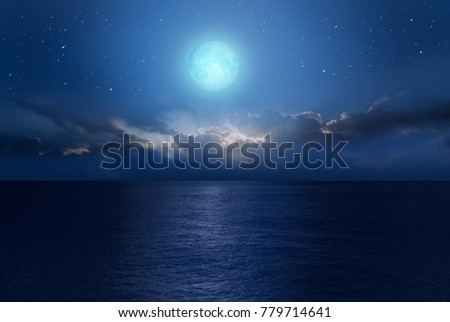 Night sky with moon in the dark clouds and darkblue sea in the foreground 