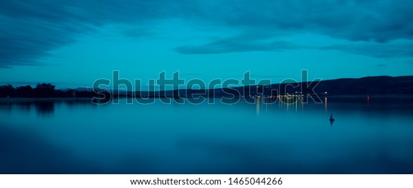 Night sky and sea. The setting\
sun and calm water. Sunset sky with clouds. Dark ocean\
water.