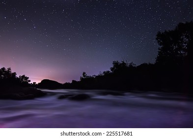 Night sky with lot of shiny stars, rocks and fast flowing water are at front - Shutterstock ID 225517681