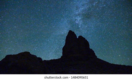 NIGHT SKY TIME LAPSE: Amazing starry night at Boars Tusk landmark in Wyoming, USA. Millions of stars and galaxies rotating above the mountaintops on clear night sky. Stars, meteors and shooting stars