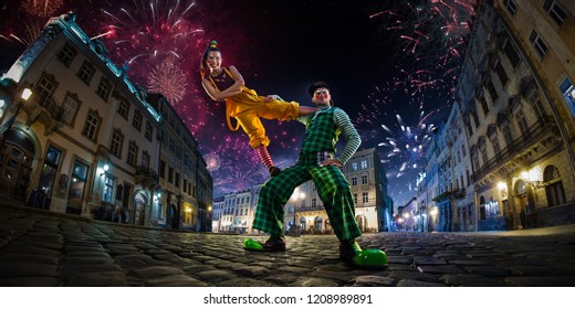 Night Street Circus Performance Whit Clown, Juggler. Festival City Background. Fireworks And Celebration Atmosphere. Wide Engle Photo