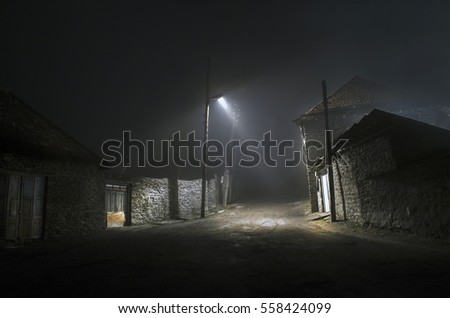Night street country road with buildings and fences covered in fog lamp . Or Mysterious night in the centre of Ilisu village Gakh, Azerbaijan