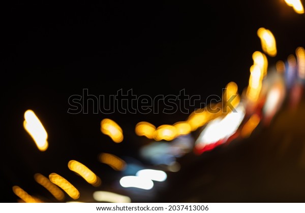 Night street illumination lights over a\
wet road. Bokeh holiday lighting. Black\
background