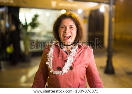 Night street portrait of smiling beautiful young woman after party and looking at camera