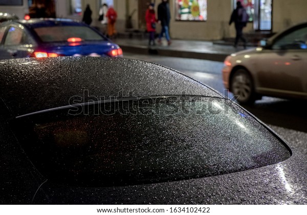 night\
street, raindrops on the tinted glass of a\
car.