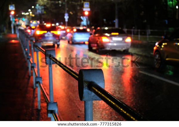 night street and reflections from the headlights\
of cars in the city in the\
rain