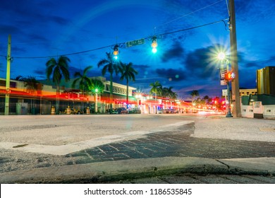 Night Time Long Exposure Of Busy Intersection In Downtown Delray Beach Florida. Light Trail From Car Vehicle Traffic Tail Lights Pass Through Green Light And Crosswalk Countdown Signal