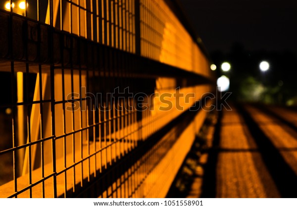 night time shot of metal fence with street light above\
in london area 