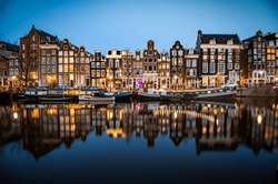 Night Time Shot Of The Singel Canal, Amsterdam With Historic Buildings Along The Bank