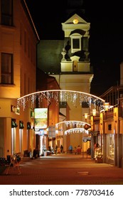 Night Town Prievidza In Slovakia, Europe. Christmas Lights And Decoration On The Store, In The Background Church.