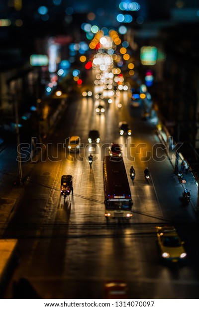 Night traffic in Bangkok. Street in the city\
center filled with cars passenger buses bikes and taxis. Night city\
lights up. Car headlights are reflected from the asphalt road\
surface.