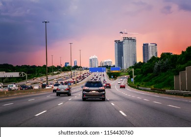 Night traffic. Cars on highway road at sunset evening in typical busy american city. Beautiful amazing night urban view with red, yellow and blue sky clouds. Sundown in downtown.