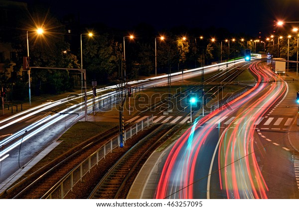 Night traffic flow in a\
city with blurred car lights and a tramway track in the middle\
(Warsaw, Poland)