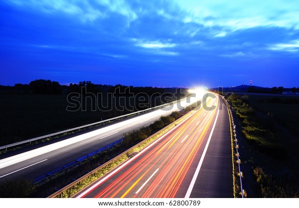 night traffic on busy highway with cars lights and
blue sky