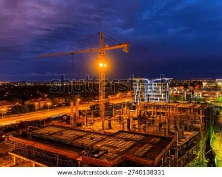 Night view of an active urban development project in Gaborone featuring a large crane, concrete structures, and the modern city skyline under a twilight sky in Botswana.