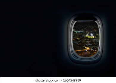 Night View from airplane porthole window of the old city of London, UK with view of river thames and St Paul’s Cathedral