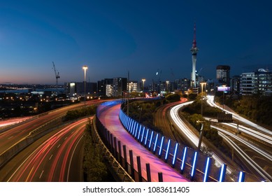 Night View Of Auckland City From Hopetoun Street Bridge With The Motorway Junction Complex And Pink Bike Path In The Foreground. Auckland, New Zealand.