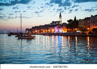 Night view of beautiful town Rovinj in Istria, Croatia. Evening in old Croatian city, night scene with water reflections and color full old buildings. Docked yachts at sunset background