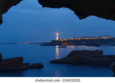 The Night View Of The Biarritz Bay And Lighthouse Seen Through Rock Natural Arch. France.