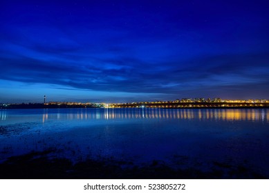 Night View At Blue Hour Of Galati City, Romania With Reflections In Danube River And Stars On Sky