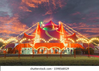Night view of a circus tent under a warn sunset and chaotic sky