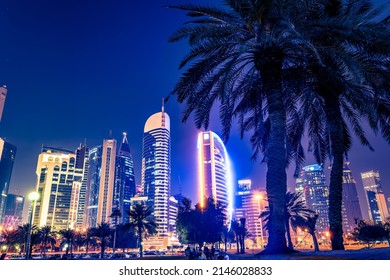 Night view in the city center of Doha, Qatar with many modern luxury buildings and skyscrapers illuminated with numerous lights.