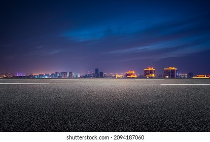 The night view of the city in front of the asphalt road