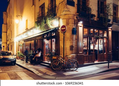 Night view of cozy street with tables of cafe and old bicycle in Paris, France. Architecture and landmarks of Paris. Postcard of Paris - Powered by Shutterstock