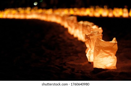 Night view of a curving line of candlelit paper lanterns set up on a beach for Marine Day in Japan - Powered by Shutterstock