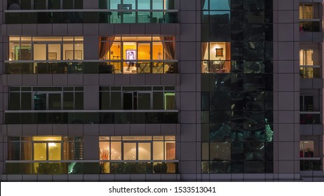 Night View Of Exterior Apartment Building Timelapse. High Rise Skyscraper With Blinking Lights In Windows With People Moving Inside. Pan Down