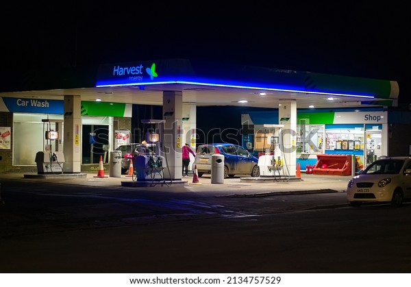 Night view of a Harvest energy service station on\
the High St.with a woman filling up a car. Boston lincolshire UK.\
Feb 2022