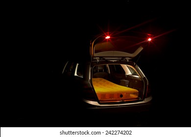 Night View Of An Illuminated Open Car Boot On An Estate Car Or Station Wagon With A Mattress Inside