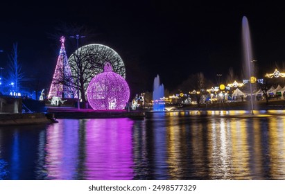 Night view of a park decorated with colorful Christmas lights reflected on the water - Powered by Shutterstock