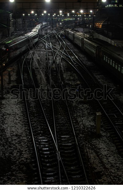 Night view of the railway tracks. Aerial view\
of the entrance to the railway station. The interlacing of railway\
tracks with shiny in the light of lanterns rails and cars on the\
sidelines.