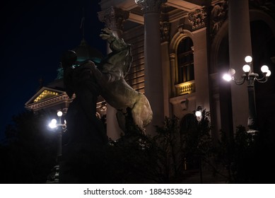 Night View Of A Sculpture Of A Man And A Horse On The Porch Of The National Assembly Of The Republic Of Serbia. A Landmark And Tourist Attraction, Beautiful Architecture. Belgrade, Serbia - 08.02.2020