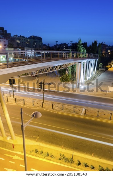 A night view of the seaside bridge connecting\
the beach to GSO Sports park in Limassol, Cyprus. A view of the\
street, the wooden and glass pedestrian bridge, Fytideio sports\
park and paraliakos.