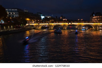 Night View Of Seine River With Pont Neuf Bridge, Touristic Ship And Two Police Boats Coming To The Rescue. Paris, France.