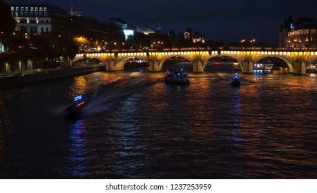 Night View Of Seine River With Pont Neuf Bridge, Touristic Ship And Two Police Boats Coming To The Rescue. Paris, France.