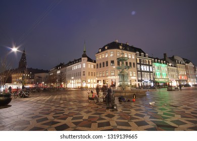 Night View Of The Street Life In The Center Of Copenhagen At Amagertorv, Stork Fountain And Cafe Europe, Christiansborg Palace In The Background, Denmark,  01 22 2019