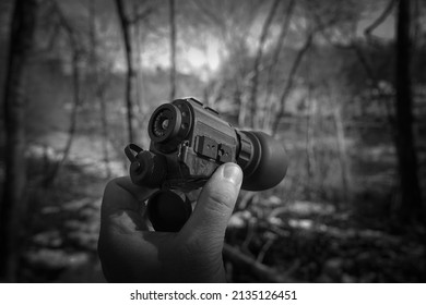 Night Vision Device In Hand Against The Backdrop Of A Forest, Black And White Close-up Photo.