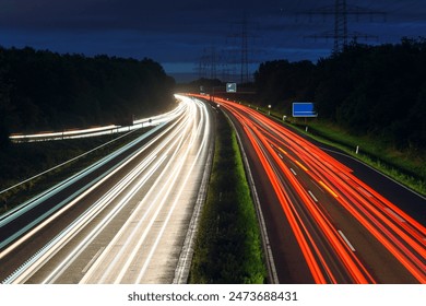 Night wiew of a motorway lined with tall high voltage pylons with light trails left by passing vehicles - Powered by Shutterstock