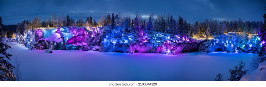 Night winter view with multi-colored illumination on the old abandoned quarry park Ruskeala. Panorama.