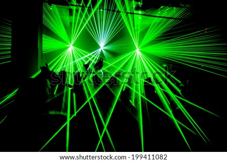 Nightclub party ravers with hands in the air and green lasers silhouette