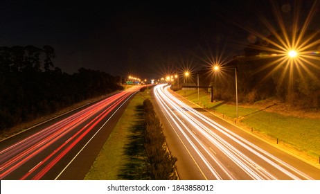Nightime light trails from speeding cars on motorway with starburst street lights.