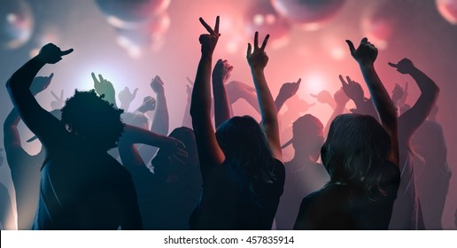 Nightlife and disco concept. Young people are dancing in club. - Shutterstock ID 457835914